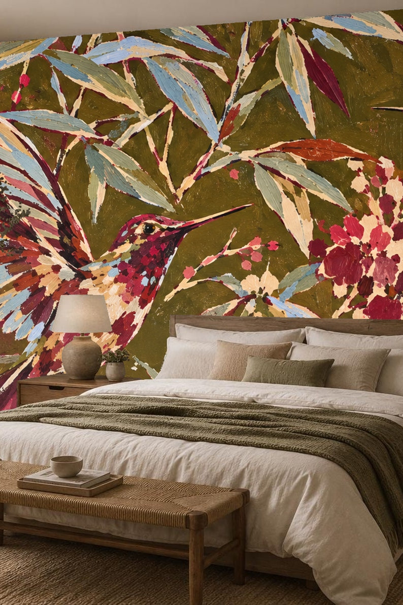 Bedroom decorated with painterly floral and hummingbird wallpaper mural in olive green and crimson hues behind bed with earth-toned bedding