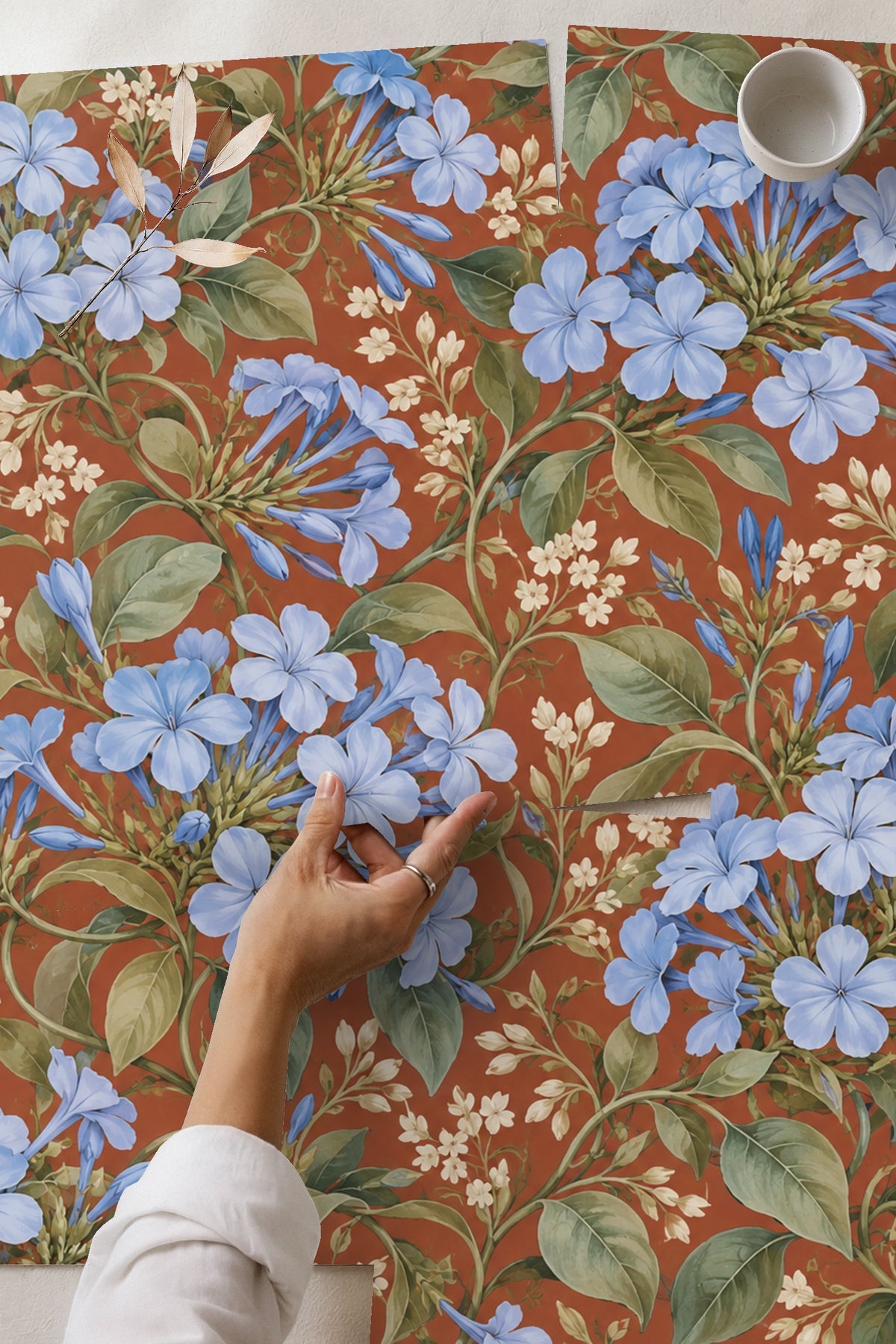 Living room wall decorated with blue plumbago floral wallpaper behind blush pink velvet chair