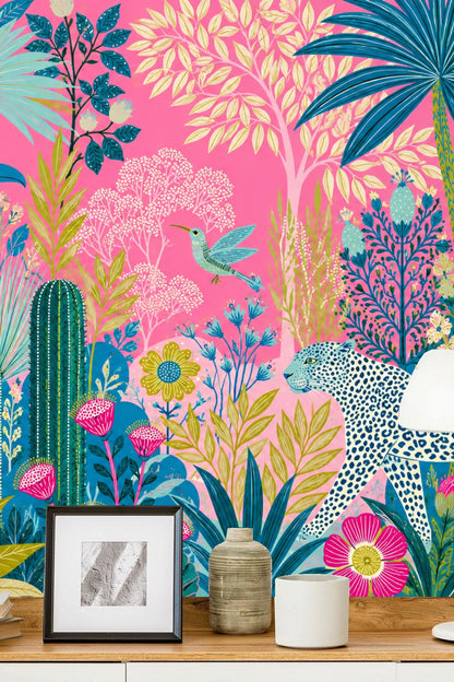Close-up of toucan perched among blue and green tropical foliage on pink background