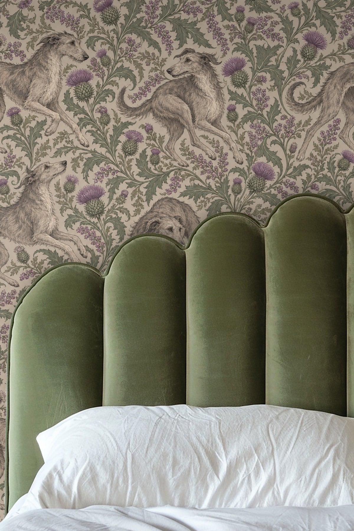 Close-up view of a candle and flowers on a wooden surface with wallpaper featuring whippets and thistles in soft greys and lavender hues