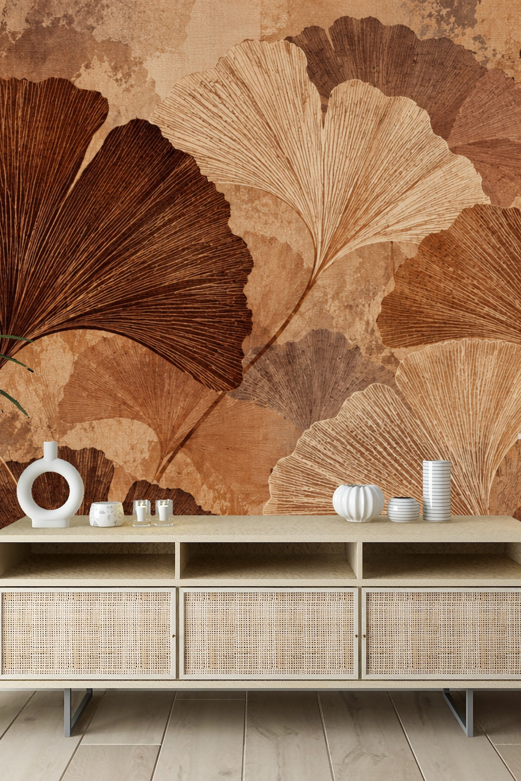 Living room scene with Ochre Ginkgo Canopy wallpaper behind a wooden bench topped with pillows and a straw hat