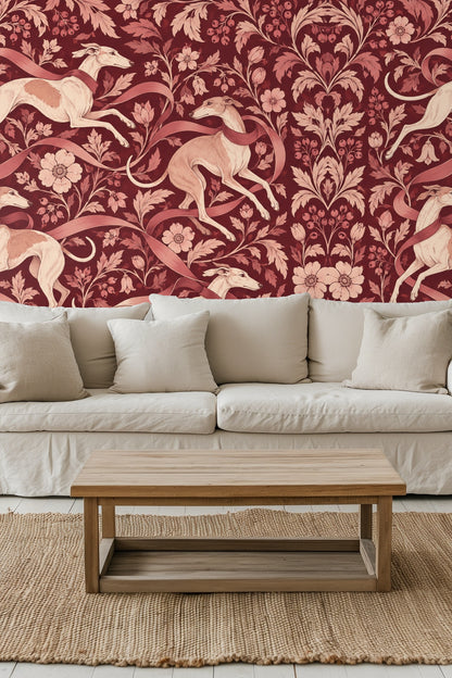 Wallpaper design with four greyhounds leaping amidst floral vines and ribbons on a burgundy background.