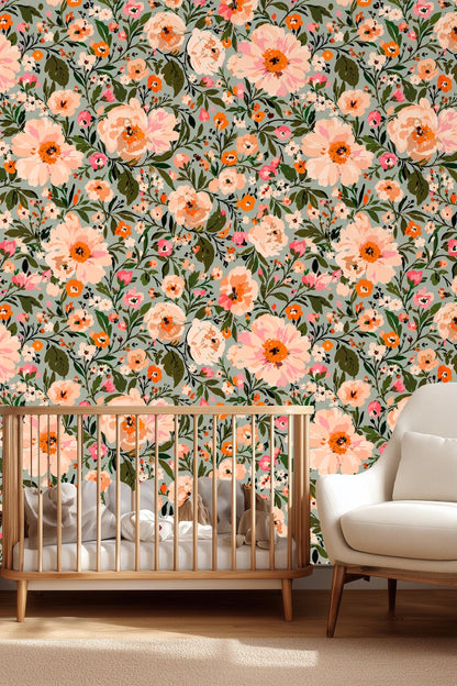 Close-up of large peach floral blossoms with green leaves on soft blue-gray wallpaper