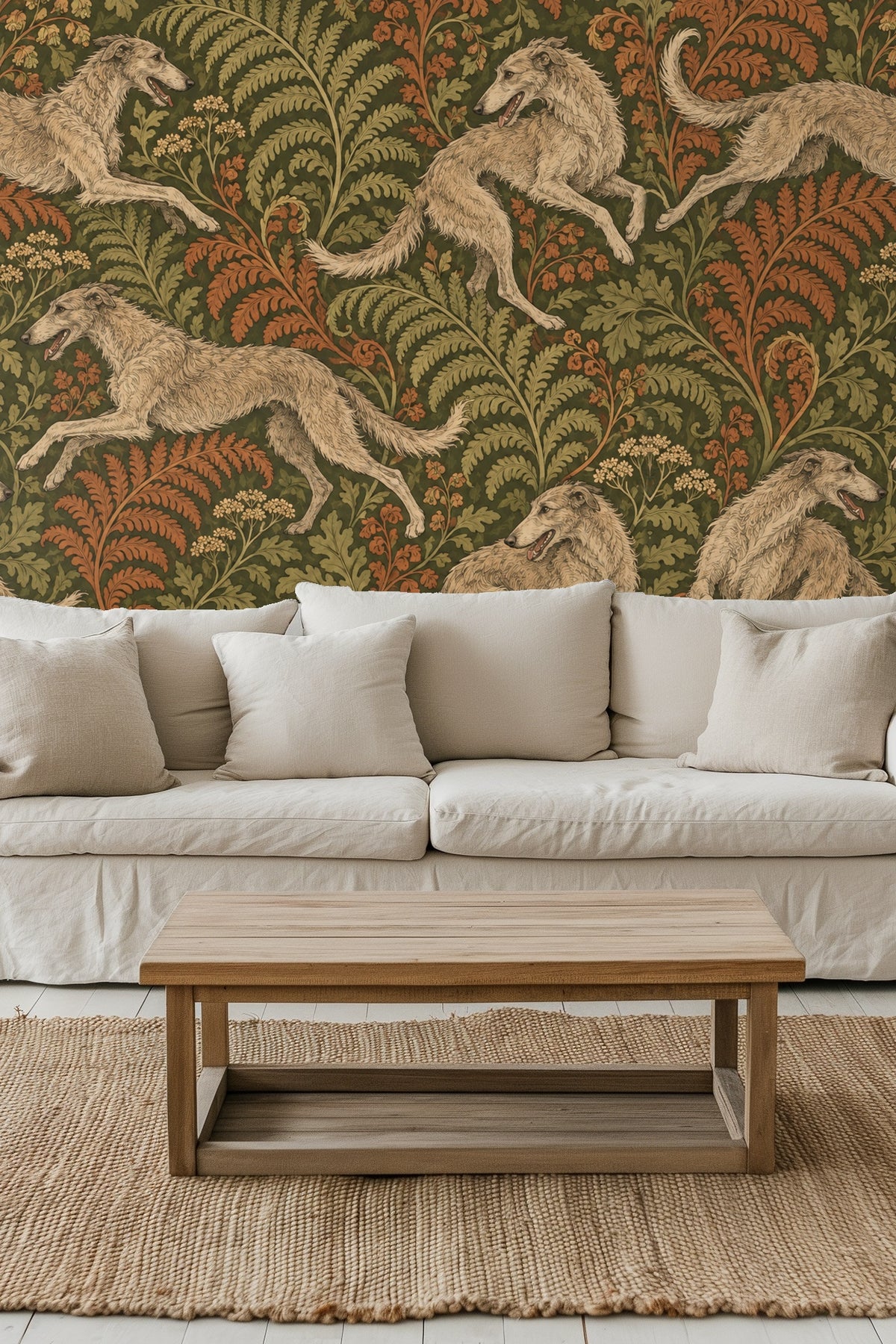 Bedroom wall with Woodland Whippet Chase wallpaper behind green velvet headboard and cream pillows.