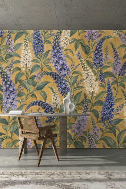 Detailed floral wallpaper featuring elongated spires of cobalt and white blossoms accompanied by detailed green leaves on mustard base.