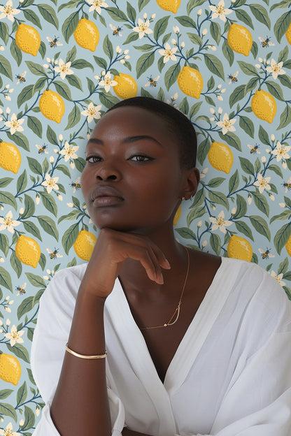 green leaves and yellow lemons intertwined on vibrant blue wallpaper
