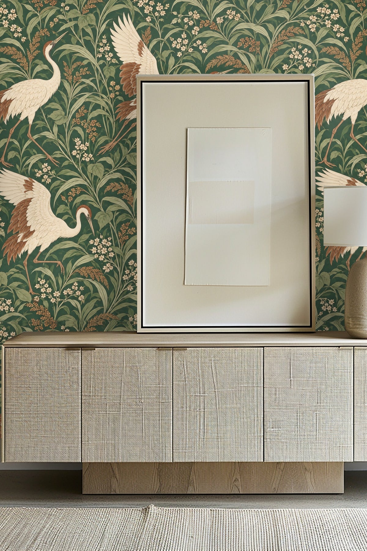 Decorative scene with Japanese Crane Meadow wallpaper backdrop, glass vase with flowers and white candle on light wood surface