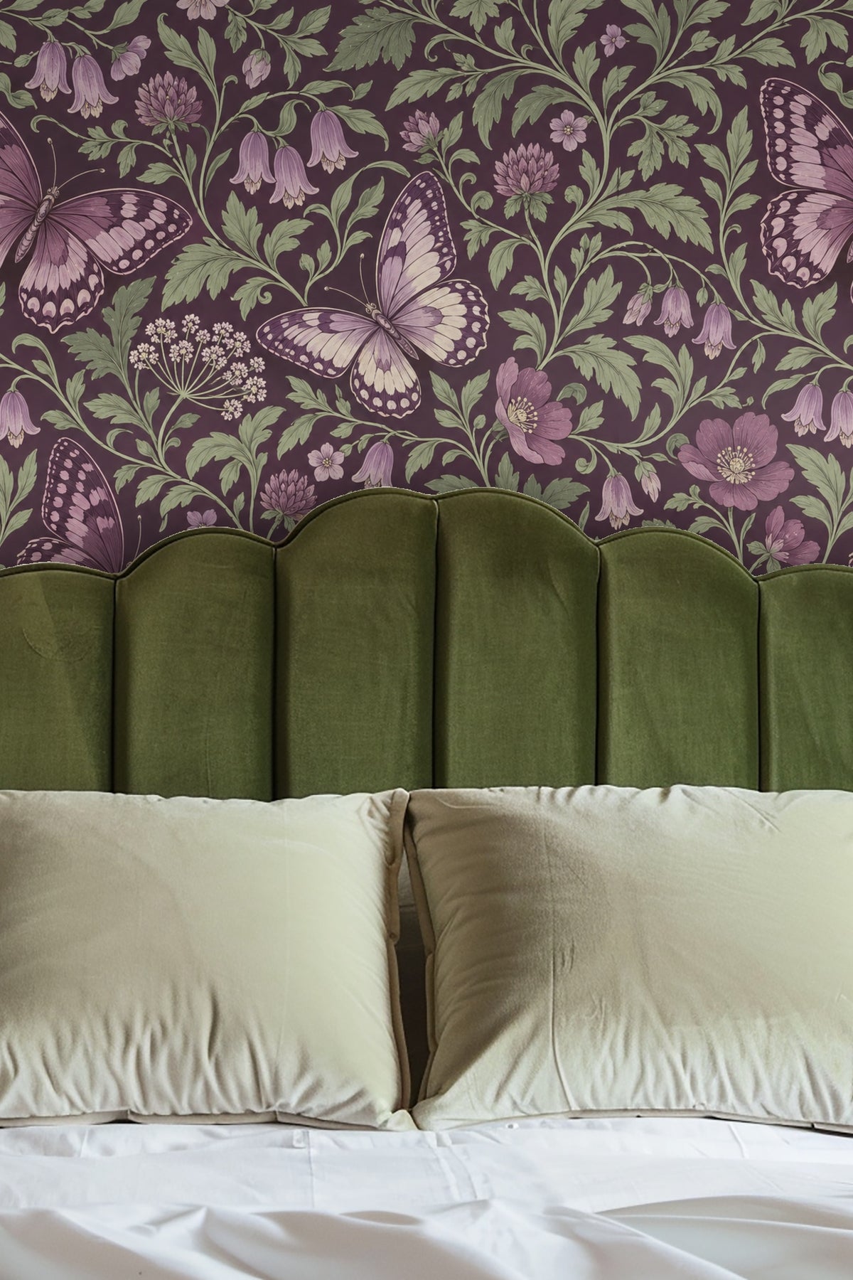 Bedroom wall featuring violet butterfly wallpaper behind olive green velvet headboard and white pillows