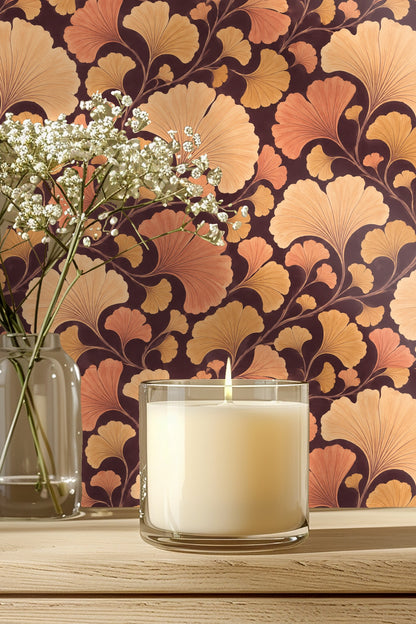 Bathroom medicine cabinet mounted on wall covered with ginkgo leaf wallpaper in warm orange and gold hues.