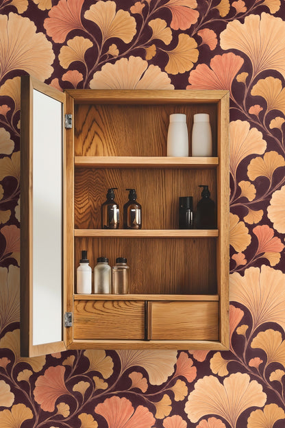 Wallpaper pattern of hand-painted ginkgo leaves in shades of apricot and amber on dark espresso background.
