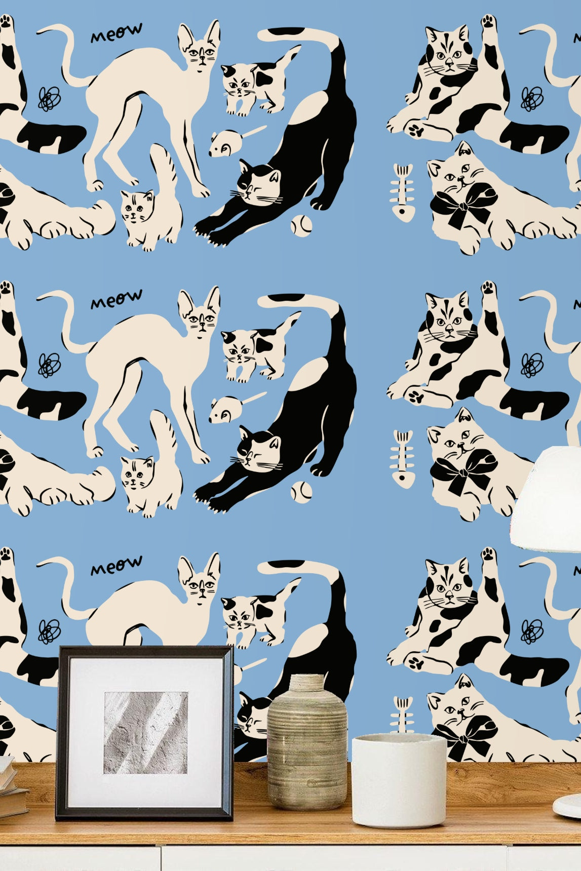 Line drawing of whimsical black and cream cats on blue surface