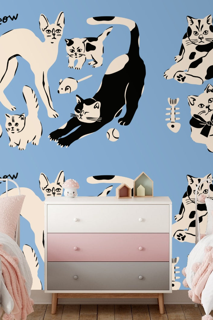 Curled kitten with large bow in black and cream on blue wallpaper