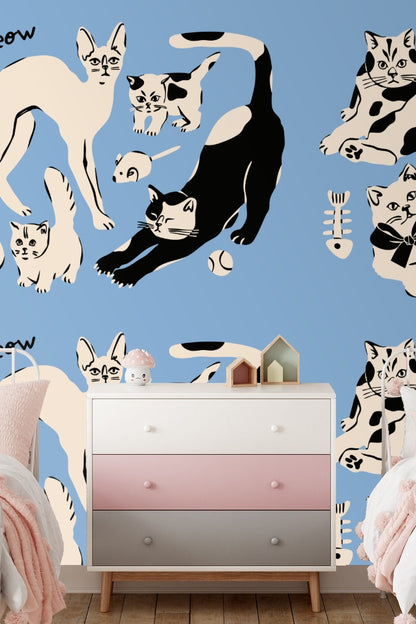 Curled kitten with large bow in black and cream on blue wallpaper