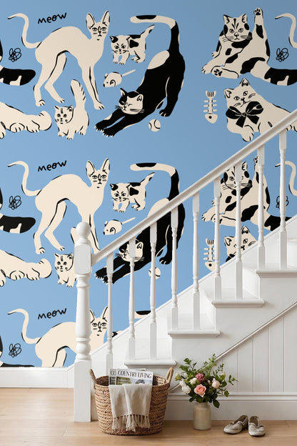 Cat with fishbone toy in black and cream on blue wallpaper
