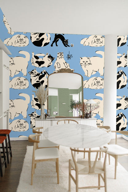 Living room scene with tan sofa and blue wallpaper featuring playful cats pattern