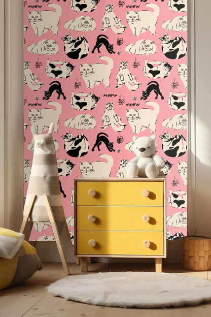 Close-up of pink wallpaper featuring black and cream cats and doodle flowers