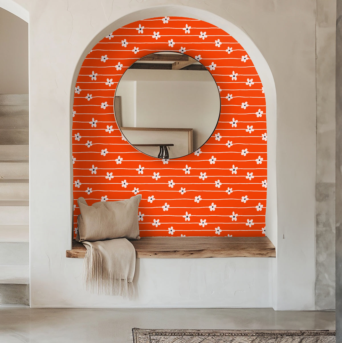 Living room view: bold orange daisy-stripe wallpaper behind a mid-century sofa and layered rugs, anchoring the seating area.