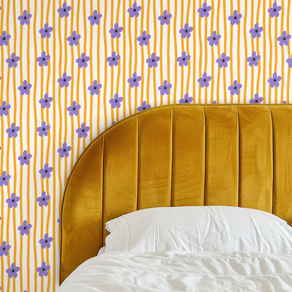 Close-up of the wallpaper pattern showing hand-drawn lavender five-petal flowers on narrow wavy saffron stripes over a warm cream background