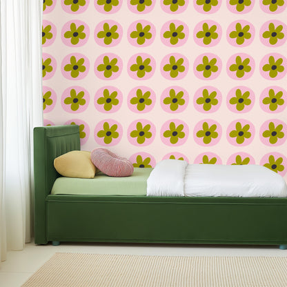 Close-up of repeating floral motif: olive green five-petal flowers centered in soft pink discs on a warm blush background.