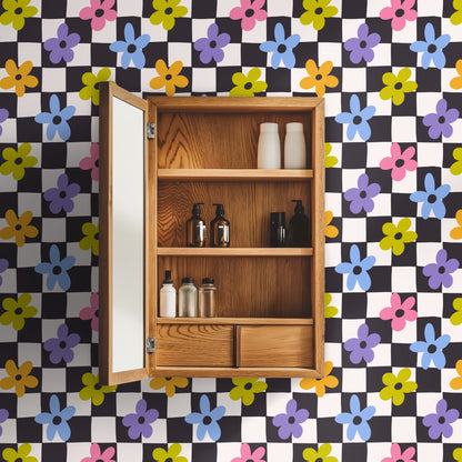 Close-up of Petal Check wallpaper: irregular charcoal and off-white checkerboard with pink, periwinkle, lilac, orange and chartreuse five-pe