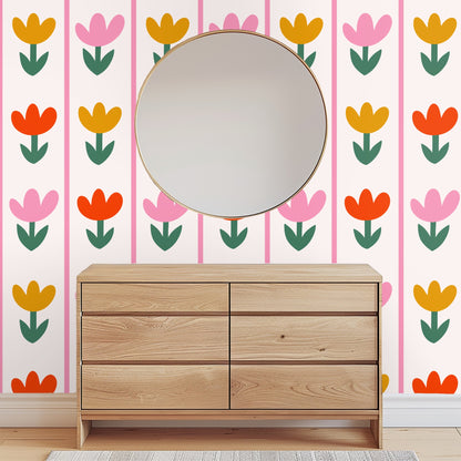 Mantel or tabletop styling with a candle and glass vase in front of Tulip Parade wallpaper, floral motif visible behind decor