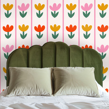 Bed with peach-velvet headboard set against Tulip Parade wallpaper, showcasing the pattern's scale and playful color story