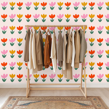 Full artwork: evenly spaced stylized tulip repeat on a pale blush background showing pink, mustard and coral blooms with green leaves