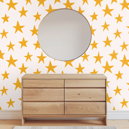 Styled shelf with a lit candle and glass vase in front of the star repeat wallpaper.