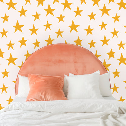 Bedroom vignette with a mustard velvet headboard set against the medium-scale star wallpaper.