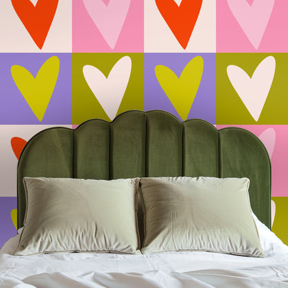 Entryway styling with a console, framed art and a table lamp against the pink, orange and olive heart mural.