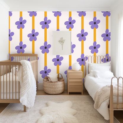 Wallpaper styled with a wooden ladder and a neutral fringed blanket, showing repeated flowers and stripes