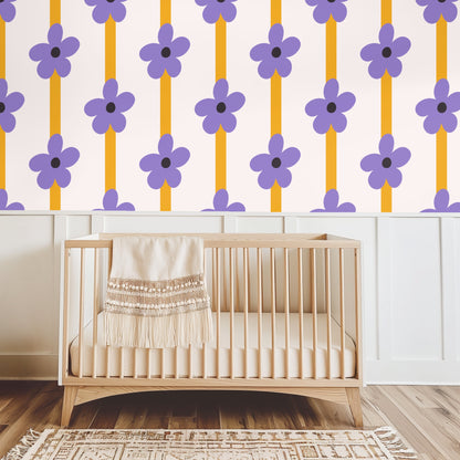 Close-up of pattern: oversized lilac five-petal flower with dark charcoal center over a mustard vertical stripe on a pale blush background