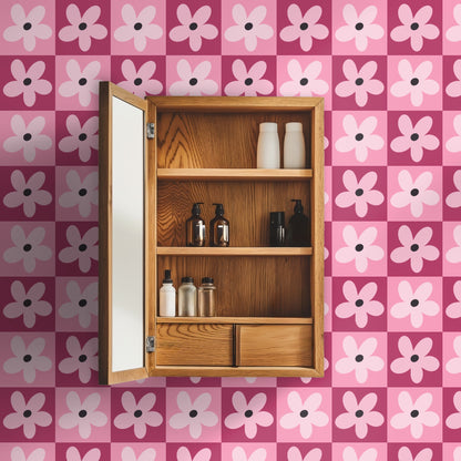Styled vignette with a candle and small glass vase set against the pink checkerboard floral wallpaper.