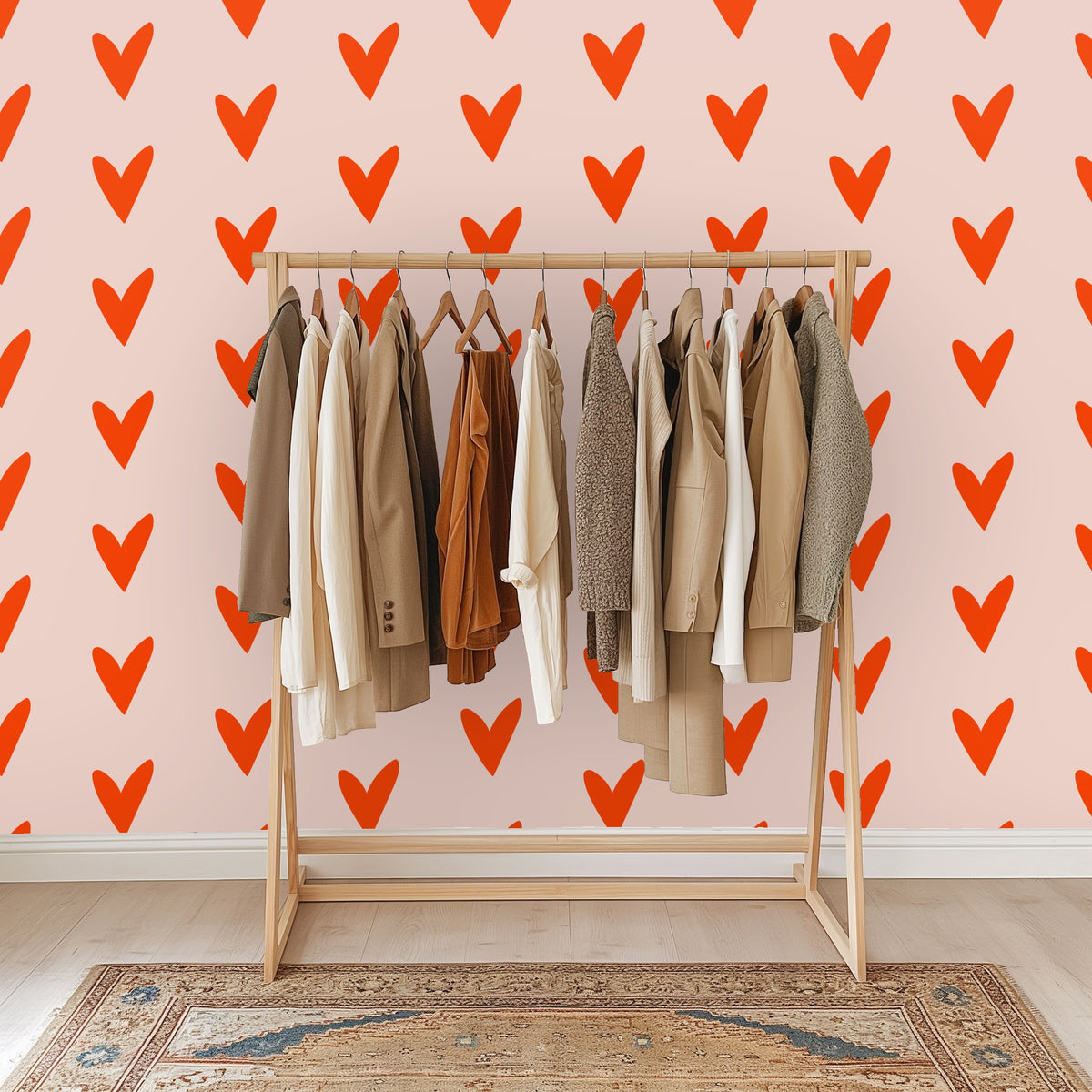 Styled close-up with a lit candle and glass vase in front of the blush wall covered in coral hearts.
