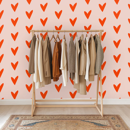 Styled close-up with a lit candle and glass vase in front of the blush wall covered in coral hearts.
