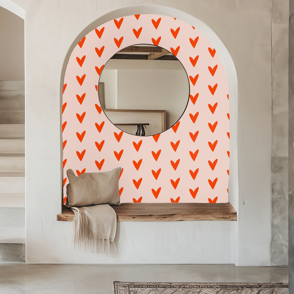 Living room vignette with an orange sofa and rug against a wall dressed in the coral heart repeat.