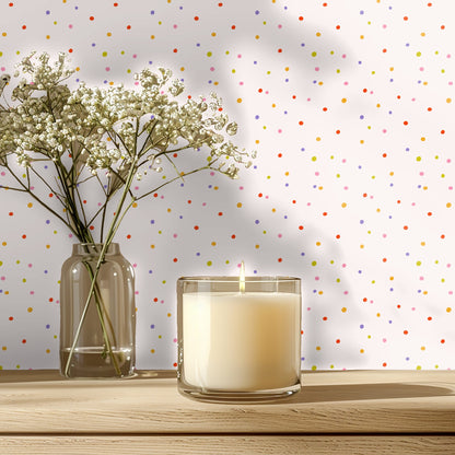 Nursery vignette showing Sweet Spot Polka wallpaper behind a light wood crib with floorboard flooring.
