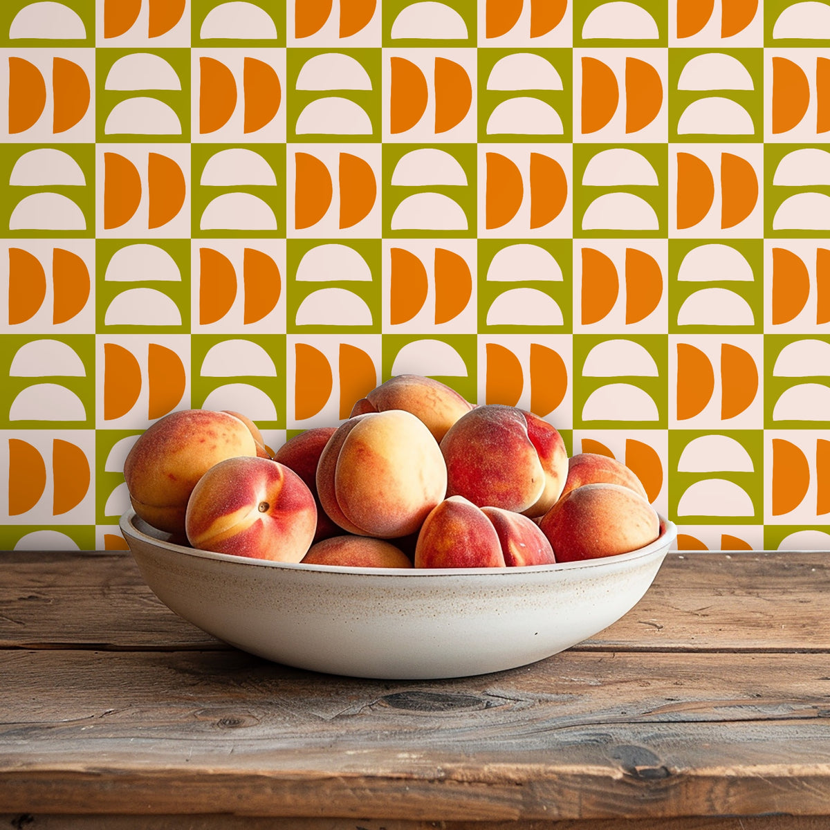 Close shot of a ceramic bowl of peaches on a wooden table with the Quartermoon Grid wallpaper pattern visible behind it.