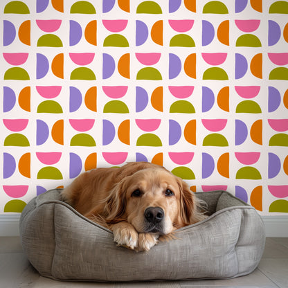 Living room installation with sofa and accent chair against the wallpaper, illustrating how the repeat reads at full-room scale.