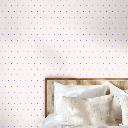 Bedroom vignette with rattan headboard against wallpaper of small lilac dots on a soft blush field