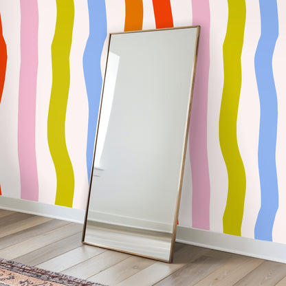 Cropped wall vignette of the large-scale wavy stripes behind a sofa, demonstrating pattern scale and color contrast with neutral furnishings