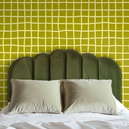 Bedroom headboard shot with scalloped green velvet against the Vireo Lattice wallpaper accent wall.
