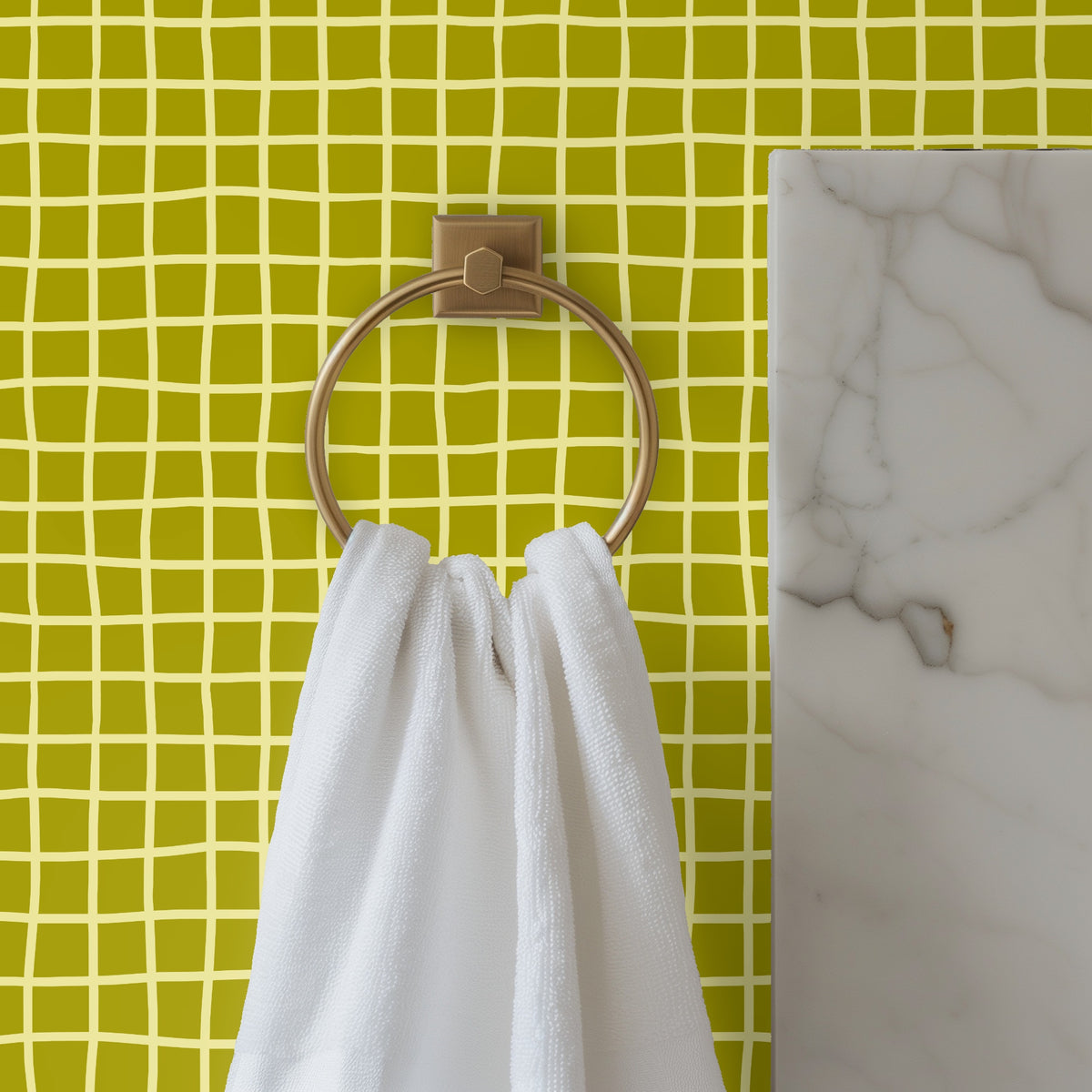 Bathroom detail with brass towel ring in front of Vireo Lattice wallpaper, showing small-scale grid and color contrast.