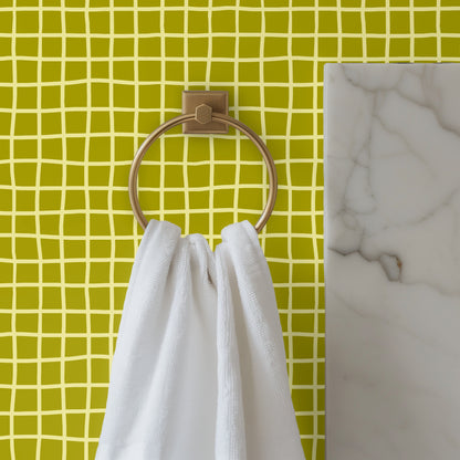 Bathroom detail with brass towel ring in front of Vireo Lattice wallpaper, showing small-scale grid and color contrast.