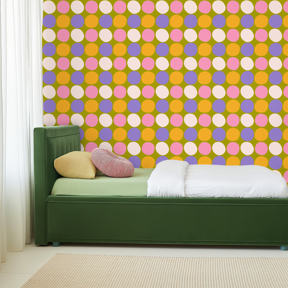 Bedroom view with green upholstered bed and Sweet Orchard Polka wallpaper filling the wall behind the headboard