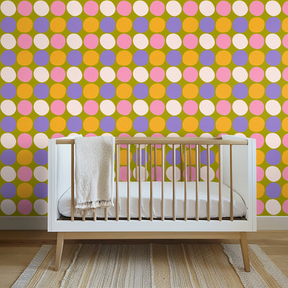 Nursery scene with white crib in front of the colorful polka wallpaper creating a lively backdrop