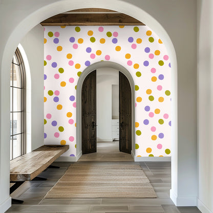 Nursery scene with light wood crib set against the confetti polka-dot wallpaper