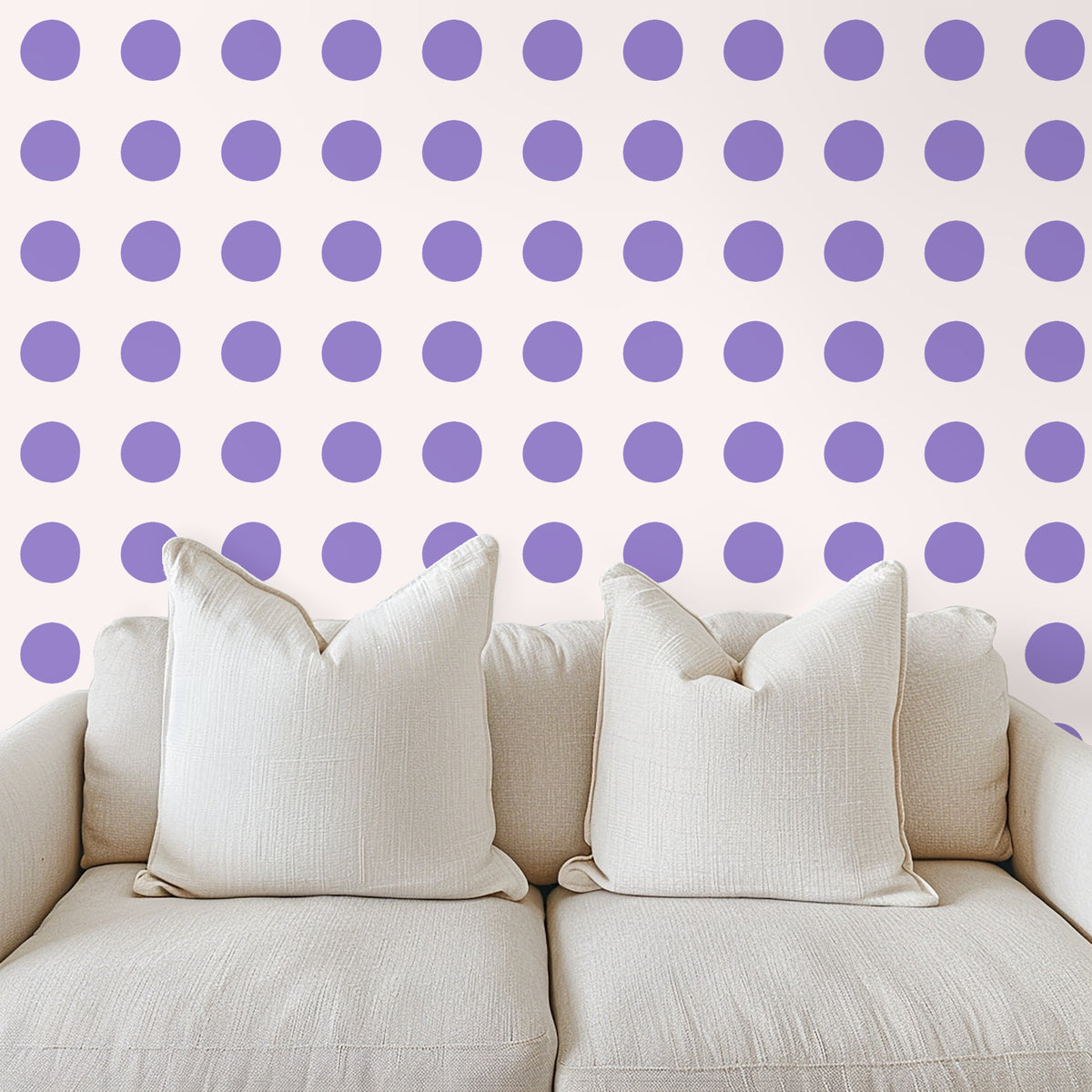 Close-up of wallpaper pattern showing irregular lilac polka dots on a warm blush background