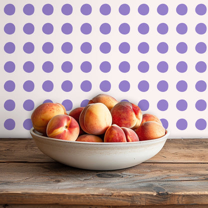 Nursery crib placed below a large-scale lilac polka dot wallpapered feature wall