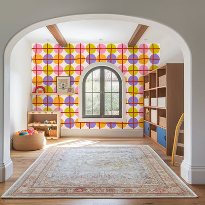 Bedroom with a full-height accent wall covered in Orbit Lattice wallpaper behind a neutral bed, showcasing the colorful circular repeat.